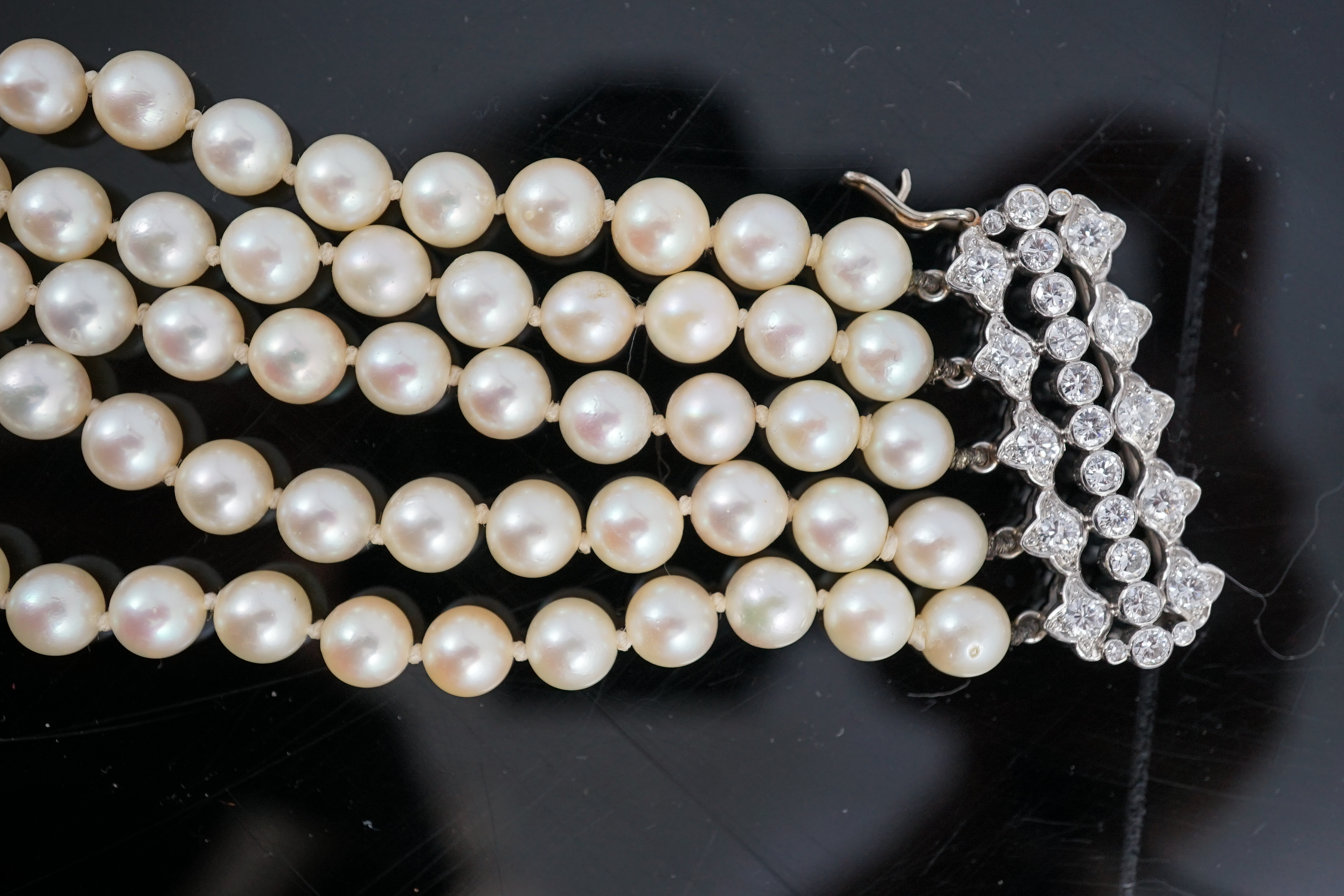 A mid 20th century quintuple strand cultured pearl choker necklace, with diamond cluster set white gold clasp and diamond cluster set white gold scrolling central motif, together with a matching bracelet